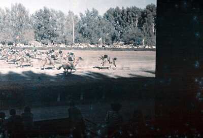 Plano general de un grupo de hombres uniformados a caballo portando banderines visto desde el sector de las gradas