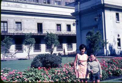 Retrato de plano medio de Mujer con Vestido y niño posando de pie en el patio de los Naranjos en el Palacio de la Moneda