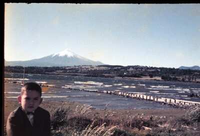 Retrato de plano medio de niño con Traje posando de frente junto al lago Villarica y volcán Villarica