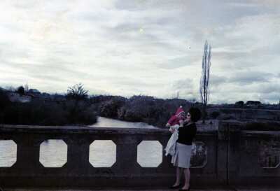 Retrato de plano entero de Mujer con Vestido y niña de temprana edad en brazos, de pie en puente Comercio de La Unión