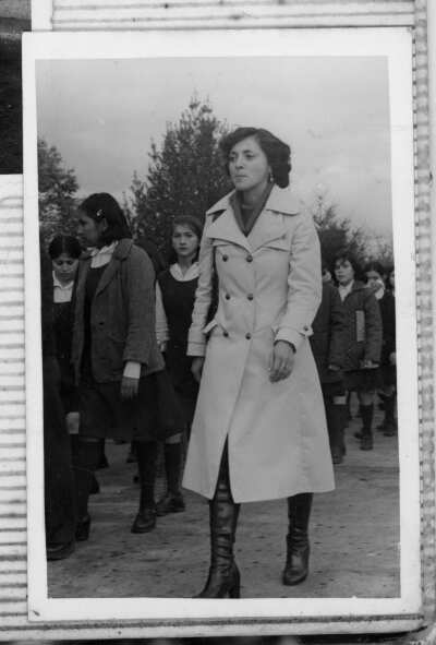 Retrato de una mujer desfilando junto a alumnos. Viste un abrigo y botas bucaneras
