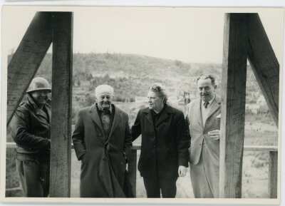 plano general de Olga Boettcher reunida con tres hombres, en el interior de una infraestructura no identificada en construcción. La fotografía fue tomada durante la visita de la gobernadora a la mina de Catamutún