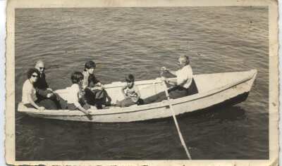 Plano entero de Hombres, una mujer, una niña y un niño en el interior de un bote. Un hombre mayor va remando mientras pasean por Lago Ranco