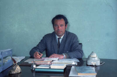 Plano medio de Enrique Larre sentado en un escritorio realizando anotaciones