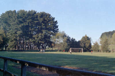 plano general de tres personas jugando a la pelota en la cancha del estadio Lino. Fotografía tomada desde las graderías del lugar