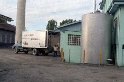 plano general de tres hombres descargando cajas de un camión en la planta de la Colum