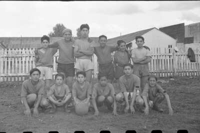 Retrato grupal de doce jugadores de un equipo de fútbol masculino juvenil, seis se encuentran de pie y  seis en cunclillas.