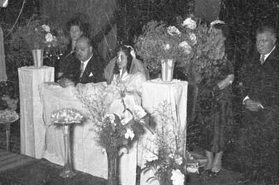 plano general de una pareja de novios, hincados en un reclinatorio, mientras sus padrinos de bodas los acompañan de pie en el altar. Están en el interior de la parroquia San José durante la misa de celebración de matrimonio
