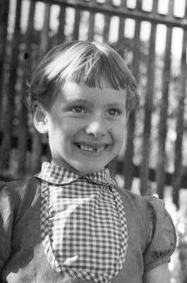 Retrato de plano medio de niña de Medio perfil mirando hacia el lado, le falta un diente de adelante