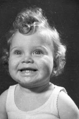 Retrato de estudio de Plano medio de una Niña de temprana edad, sonriendo mientras posa de frente mirando hacia arriba