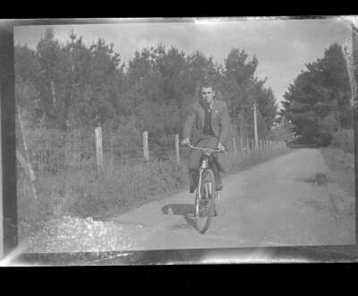Plano general de un hombre joven sobre una bicicleta andando en un camino sin pavimentar en un entorno rural